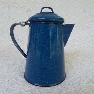 May include: A blue enamel coffee pot with a speckled finish and a silver handle. The pot has a lid and a spout.