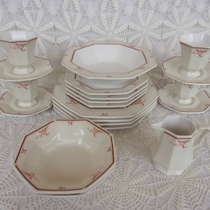 May include: A set of white porcelain dinnerware with a delicate floral pattern in shades of pink and brown. The set includes a large octagonal serving bowl, smaller octagonal bowls, plates, and teacups with saucers.