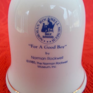 May include: White ceramic bell with a blue and white Norman Rockwell Museum seal and the text "For A Good Boy" by Norman Rockwell &copy;1985, The Norman Rockwell Museum, Inc.