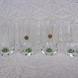 May include: Set of four clear glass highball glasses with a green base and a ribbed design. Each glass has a small, round, gold label with the text "RCR Cristalleria Italiana" on it.