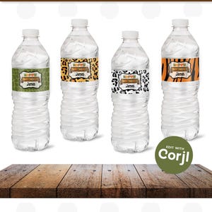 May include: Four clear plastic water bottles with labels that say "Happy Birthday James" in a jungle animal print theme. The labels have a brown woodgrain background and feature a variety of animal prints, including leopard, zebra, and giraffe. The bottles are sitting on a wooden surface.