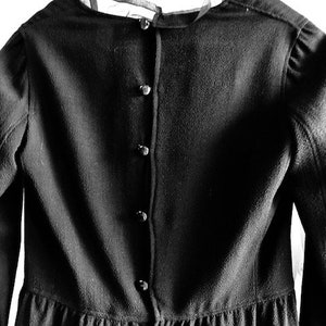 May include: Black dress with a button-up back and a ruffled hem.