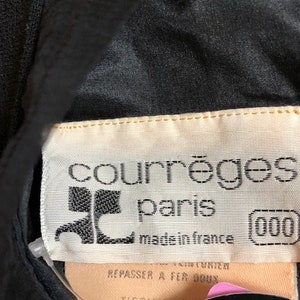 May include: A black garment with a white label that reads "courr&egrave;ges paris made in france (000)". The label also includes instructions to iron at 900 degrees and the fabric composition is 100% matte.