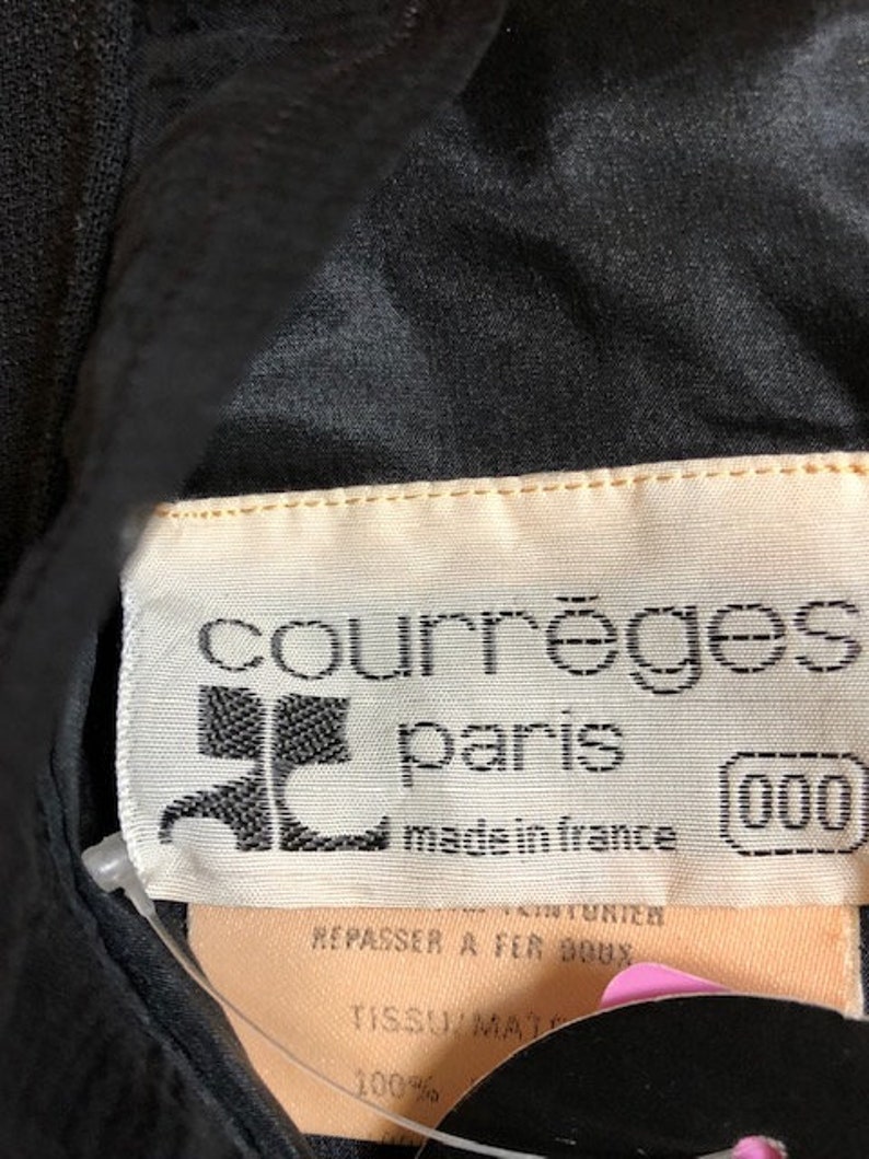 May include: A black garment with a white label that reads "courr&egrave;ges paris made in france (000)". The label also includes instructions to iron at 900 degrees and the fabric composition is 100% matte.