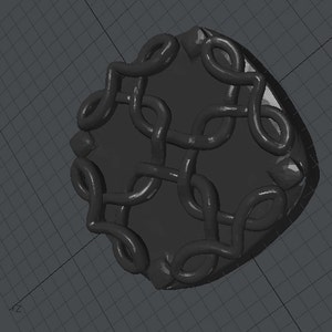 Puede incluir: Un anillo negro con un diseño intrincado en forma de nudo. El anillo está hecho de un material liso y brillante y tiene un diseño texturizado en relieve.