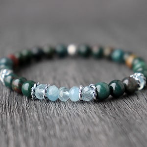 以下が含まれることがあります： 緑と青の宝石のブレスレットで、銀のアクセントが施されています。ブレスレットは丸いビーズで作られており、シンプルなデザインです。