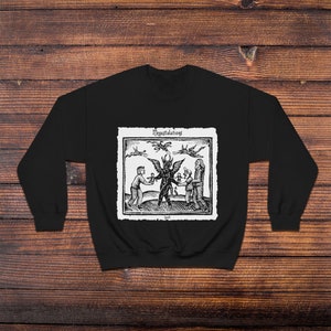 May include: Black sweatshirt with a white print of a black and white illustration of a devil with two people and three flying bats. The text "Megastalations" is above the illustration and the text "Evil" is below the illustration.
