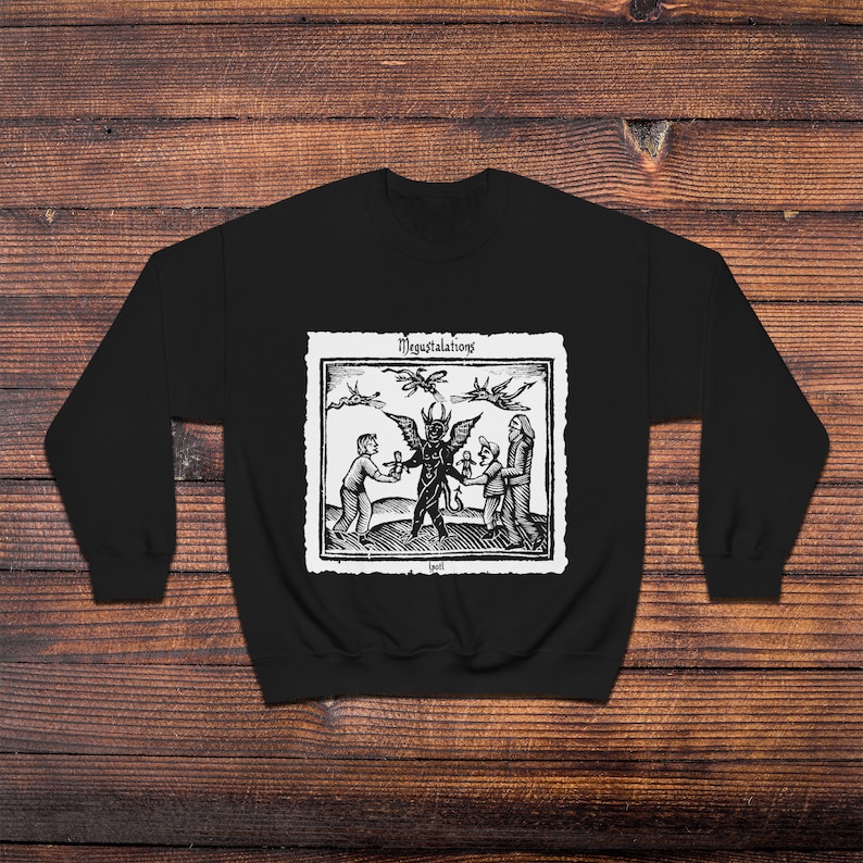 May include: Black sweatshirt with a white print of a black and white illustration of a devil with two people and three flying bats. The text "Megastalations" is above the illustration and the text "Evil" is below the illustration.