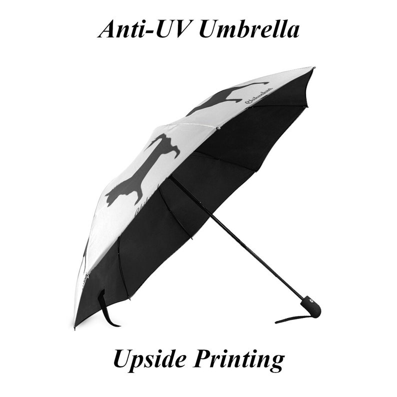 May include: A black and white Anti-UV umbrella with upside printing. The umbrella features a black dachshund silhouette on a white background. The umbrella is open, displaying its full shape and design.