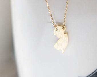 May include: A gold necklace with a pendant shaped like the state of New Jersey.