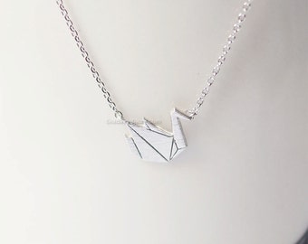 May include: A silver chain necklace with a silver origami crane pendant.