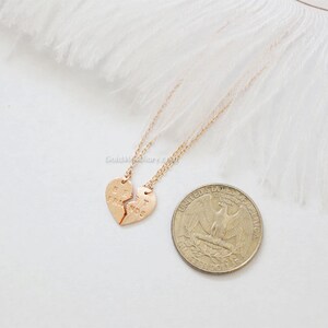 May include: Two gold necklaces with matching heart pendants that say "Best Friends" on them. The necklaces are on a white feather background.