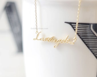 May include: A gold necklace with a cursive script pendant that reads "Los Angeles".