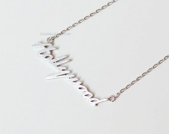 May include: A silver chain necklace with a cursive "Hollywood" pendant.