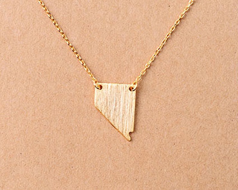 Puede incluir: Un collar de oro con un colgante con forma del estado de Nevada.