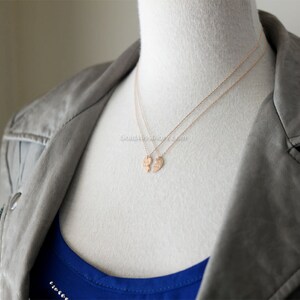 May include: Two gold necklaces with matching heart pendants. The pendants are split in half, with each half forming a complete heart when worn together.