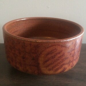 May include: A brown ceramic bowl with a speckled glaze. The bowl has a rounded shape and a wide rim.