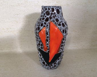 May include: A brown and white ceramic vase with a geometric orange design. The vase has a textured surface.