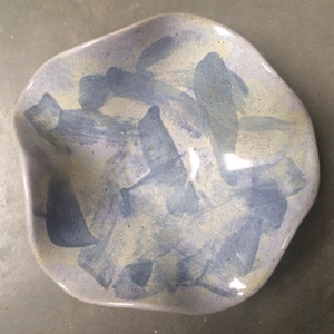 May include: A handmade ceramic dish with an organic shape. The dish features a light blue base with abstract brushstrokes in darker blue and cream colors. The dish is suitable for serving or display.