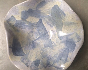 May include: A handmade ceramic dish with an organic shape. The dish features a light blue base with abstract brushstrokes in darker blue and cream colors. The dish is suitable for serving or display.