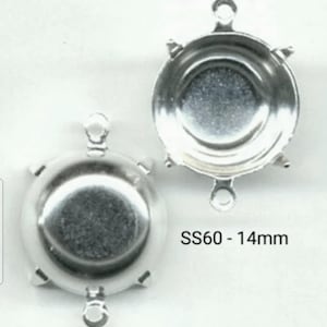 Pode incluir: Dois engastes de metal prateados para uma pedra redonda de 14 mm. Cada engaste tem três laços para prender a uma peça de joalheria. O texto "SS60 - 14mm" é visível na imagem.