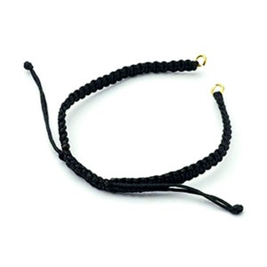 Puede incluir: Un brazalete trenzado negro con cierres de metal dorado.