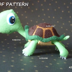 May include: A green felt turtle with a brown shell and big blue eyes. The turtle is walking on a gray background with white stars.