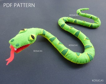May include: A green felt snake with a red tongue and yellow eyes. The snake has a green and yellow patterned design. The image includes the text "PDF PATTERN" and "KOSUCAS".