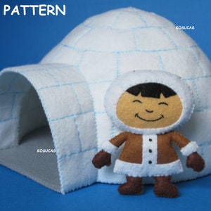 May include: A white felt igloo with a blue stitched pattern and a small felt figure of a person wearing a brown coat and a white hood. The igloo has a grey felt entrance.