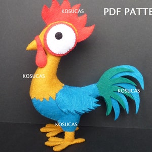 May include: A felt rooster toy with a yellow body, blue wings, and a red comb. The rooster has a white-rimmed eye and a yellow beak. The text "PDF PATTERN" is visible in the upper right corner. The rooster is a handmade craft.