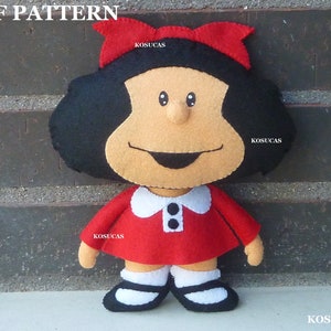 May include: A felt doll of a girl with black hair, a red dress, and a red bow. The doll has a white collar with two black buttons. The doll is standing in front of a brick wall.