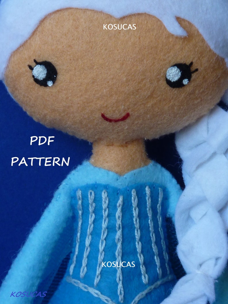 May include: A blue felt doll with white hair, a blue dress with white embroidery, and a red smile. The doll is holding a white felt braid. The text "PDF PATTERN" and "KOSUCAS" is visible on the image.