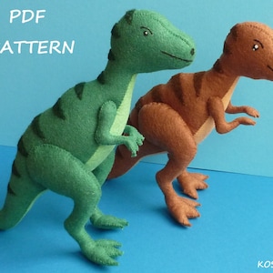 Può includere: Modello PDF per due giocattoli di dinosauro in feltro. Un dinosauro è verde con strisce nere e l'altro è marrone con strisce nere.