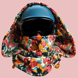 Peut inclure: Un tour de cou à motif floral coloré avec un casque de ski bleu et des lunettes de ski noires. Le tour de cou a une fermeture à cordon et des boutons en cuir marron.