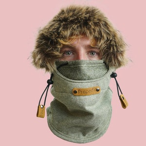 May include: A grey fleece neck gaiter with a faux fur hood and a brown leather patch that says "PreperFit".