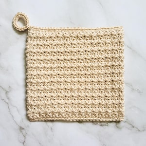 Beige Ring-Start Potholder crocheted in dense, double-thick Trinity Stitch fabric with a hanging loop. The potholder is displayed on a white marble countertop.