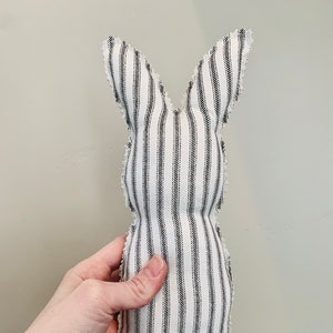 May include: A white and black striped fabric bunny rabbit with a frayed edge. The bunny is standing upright and is about 12 inches tall.