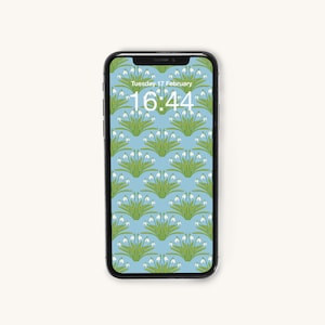 Könnte beinhalten: Ein schwarzes Smartphone zeigt einen floralen Hintergrund auf hellblauem Grund. Das Hintergrundbild hat ein sich wiederholendes Muster aus weißen Blumen mit grünen Stielen und Blättern. Der Bildschirm zeigt Datum und Uhrzeit: Dienstag, 17. Februar, 16:44.