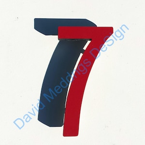 以下が含まれることがあります： 白い背景に影を落とした、赤い木製の数字7の切り抜きです。