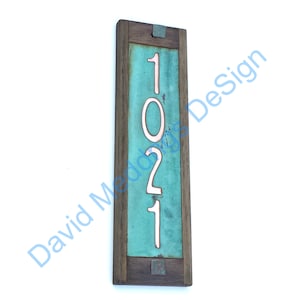 May include: A wooden framed house number sign with a turquoise background and white numbers. The numbers are 1021.