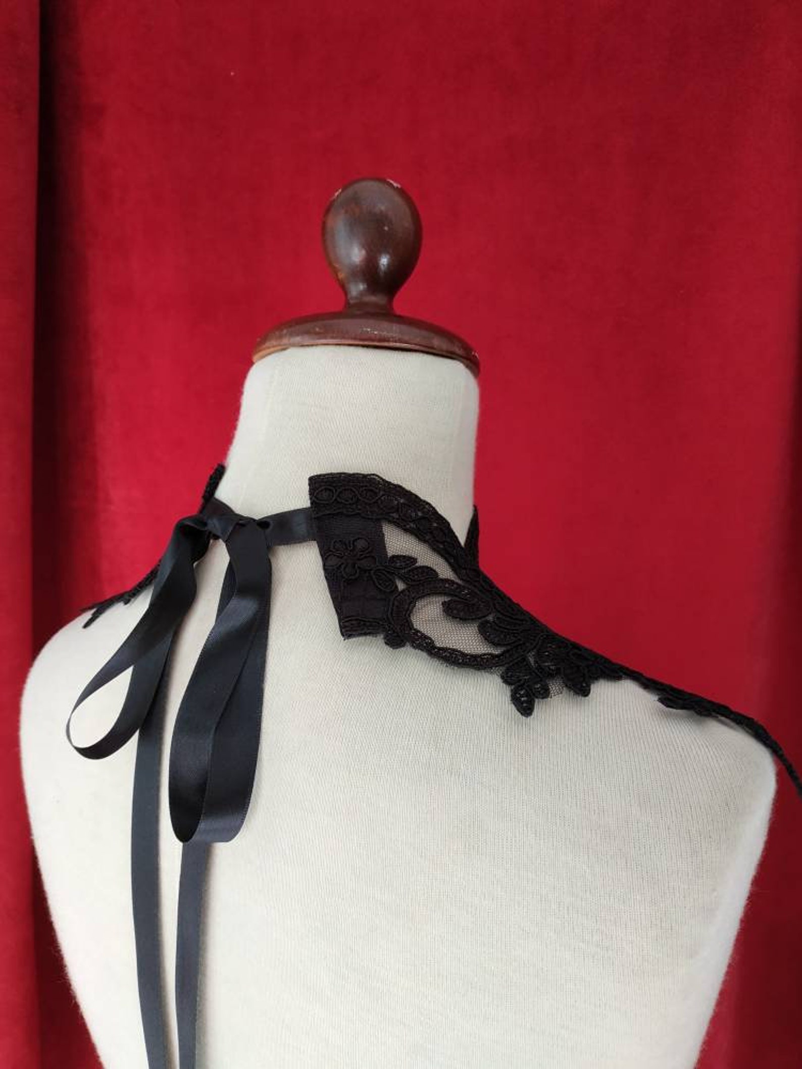 Back view of black lace choker tied with long satin ribbon bow on mannequin.
