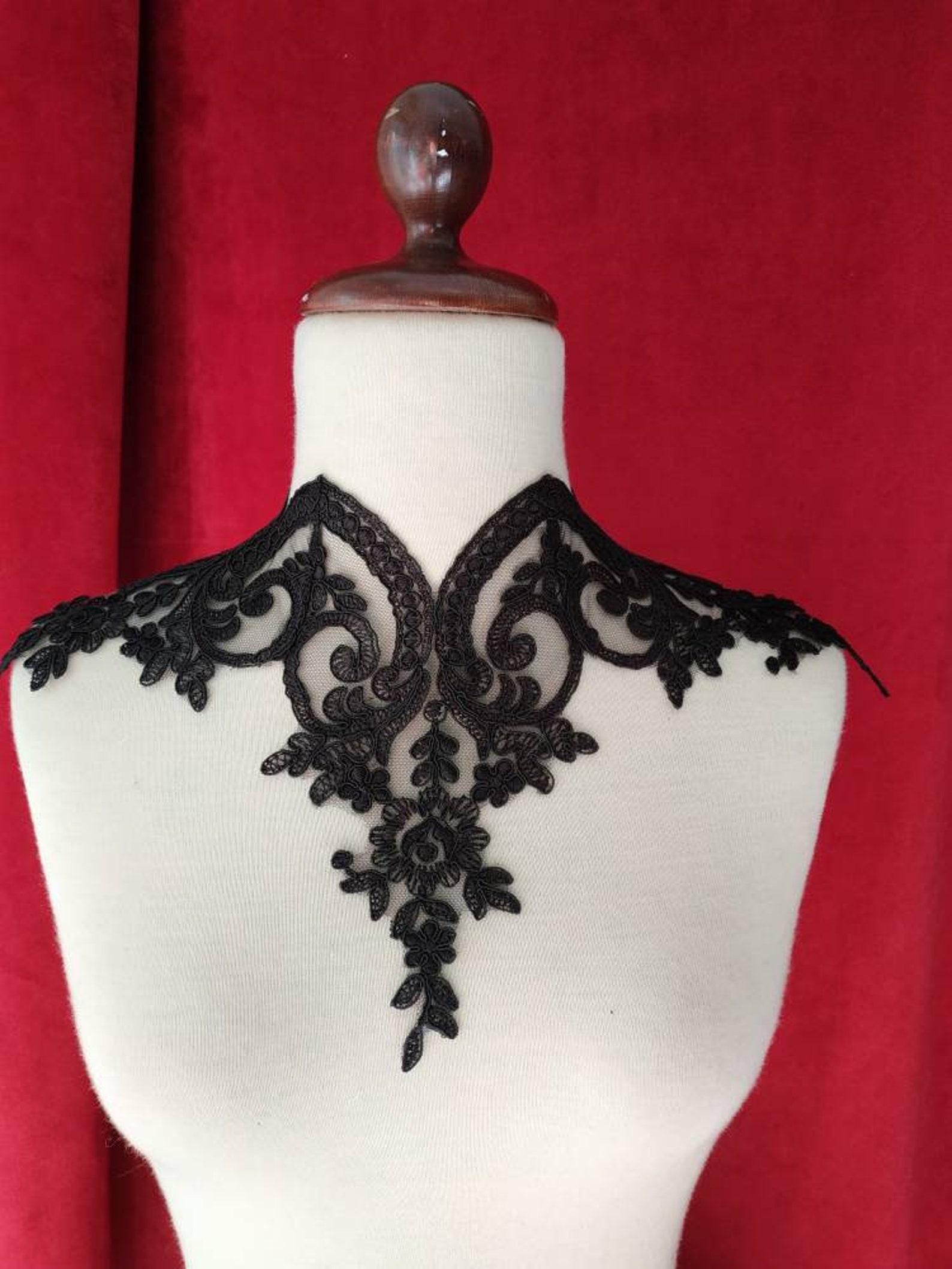 Front view of black lace gothic choker with delicate scrolls and floral details on white mannequin.