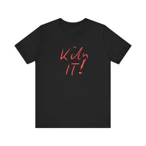 Può includere: T-shirt nero con la scritta rossa "Kill It!" in stile manoscritto. La maglietta girocollo ha il testo centrato sul davanti. Il tessuto sembra morbido. Il design è semplice e audace.