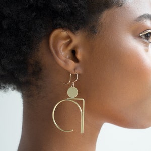 Black Woman in Abstract Gold Geometric Statement Earrings. 
Made by L.Greenwalt Jewelry of Portland, OR.