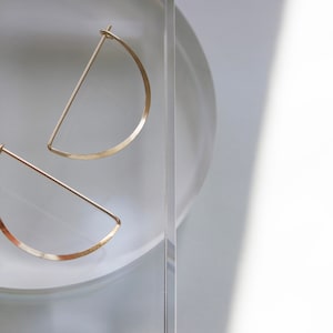 Minimalist Gold Crescent Earrings on soft white light dappled background. 

Made by L.Greenwalt Jewelry of Portland, OR.