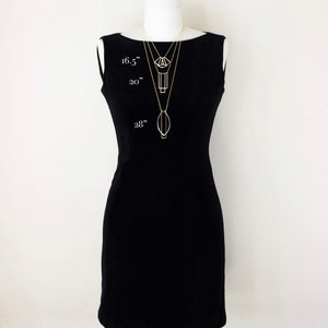May include: A black sleeveless dress on a mannequin with three gold necklaces of varying lengths. The necklaces are 16.5", 20", and 28" long, each with a unique geometric pendant. The mannequin is set against a white background.