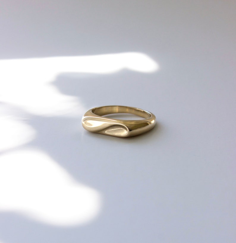 Gold Abstract infinity signet ring on soft white dappled light background. 
made by L.Greenwalt Jewelry of Portland, OR.