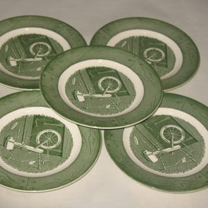 Può includere: Cinque piatti decorativi verdi e bianchi. Ogni piatto presenta un'illustrazione centrale di un filatoio e degli attrezzi. I piatti hanno un bordo verde e un anello interno bianco.