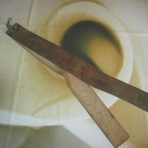 May include: A vintage leather strop with a wooden handle and a metal clasp. The strop is a dark brown color and is used for sharpening straight razors. The image shows the strop at an angle, with the leather surface visible.