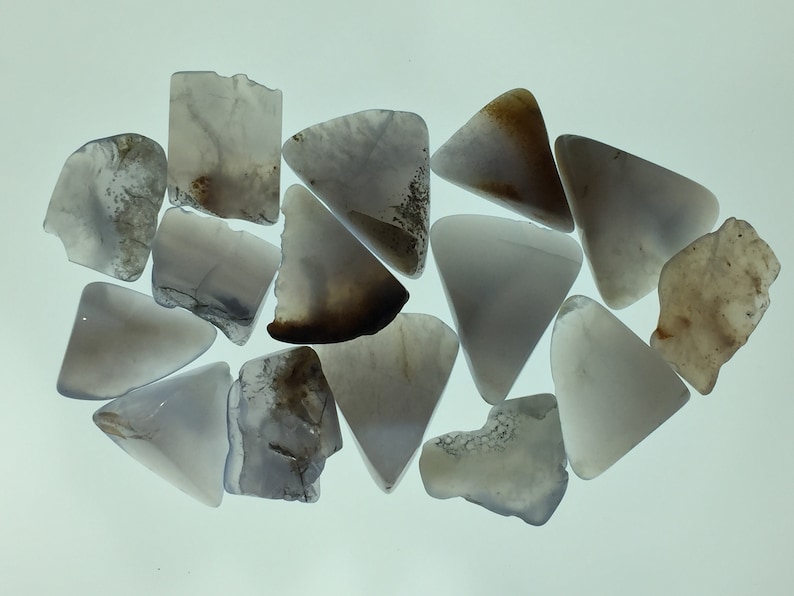 May include: A collection of 13 grey and brown agate chips, some with a triangular shape, others with irregular shapes.